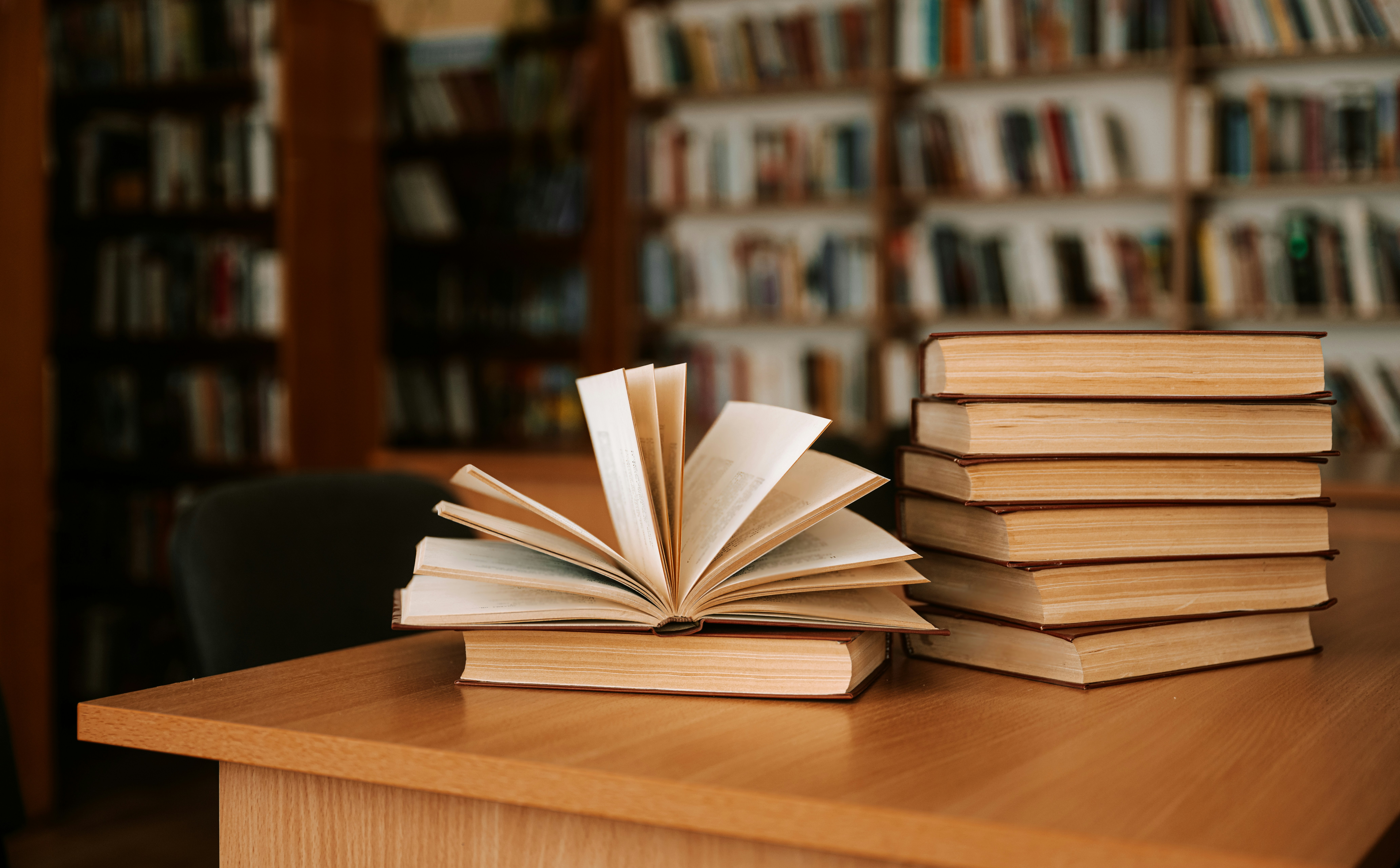 A stack of law textbooks on a desk, surrounded by bookshelves in a library, representing law students and representing clients in POA Court in Ontario